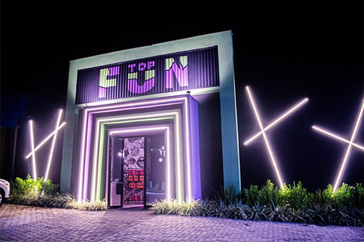 Fachada do Top Fun Eventos à noite, iluminada em neon verde e roxo